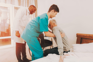 senior man assisted by caregiver to stand